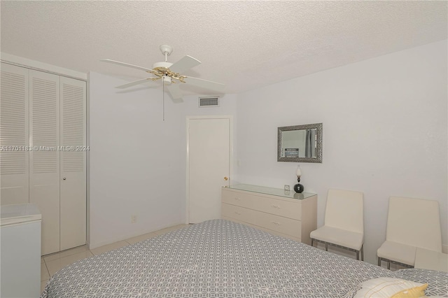 tiled bedroom with a textured ceiling, a closet, and ceiling fan