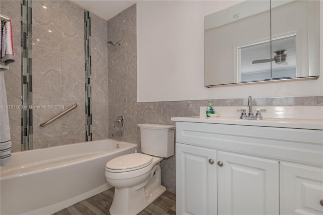 full bathroom with tiled shower / bath combo, wood-type flooring, toilet, vanity, and tile walls