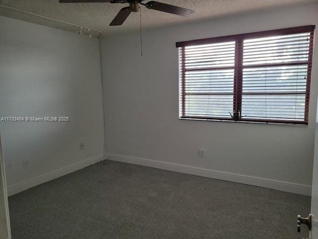 empty room with ceiling fan, dark carpet, and a textured ceiling