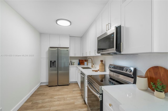 kitchen with sink, tasteful backsplash, appliances with stainless steel finishes, light hardwood / wood-style floors, and white cabinets