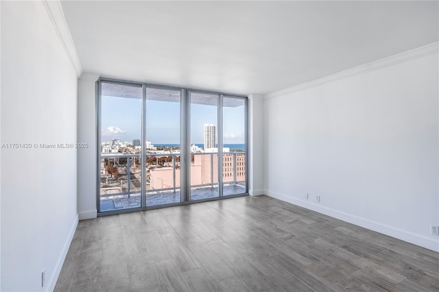 empty room with ornamental molding, floor to ceiling windows, and hardwood / wood-style floors