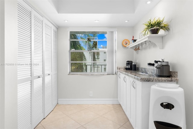 kitchen featuring white cabinets, stone countertops, and light tile patterned floors