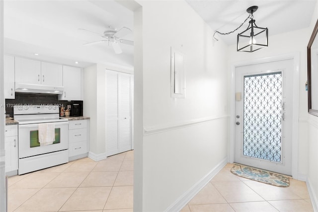 interior space featuring backsplash, pendant lighting, electric range, light tile patterned floors, and white cabinetry