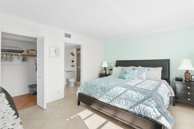 tiled bedroom featuring ensuite bath, a closet, and ornamental molding