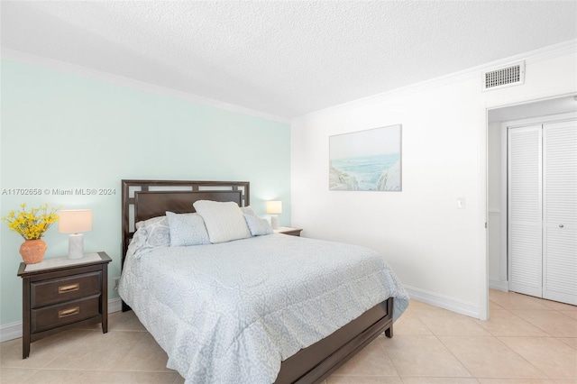 bedroom with light tile patterned flooring, ornamental molding, and a textured ceiling