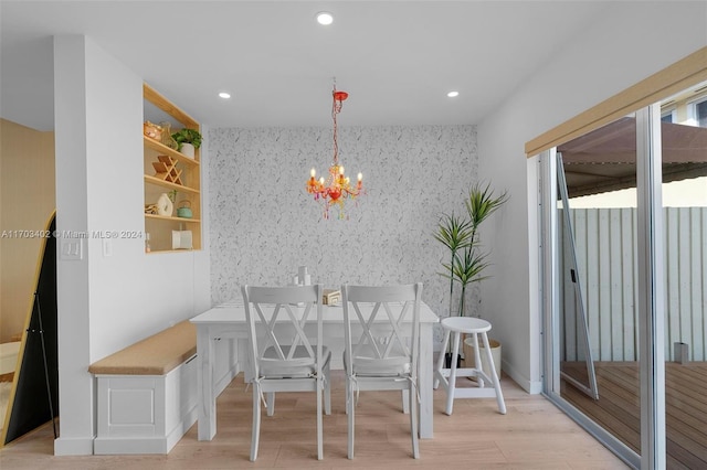 dining area with light wood-type flooring and an inviting chandelier