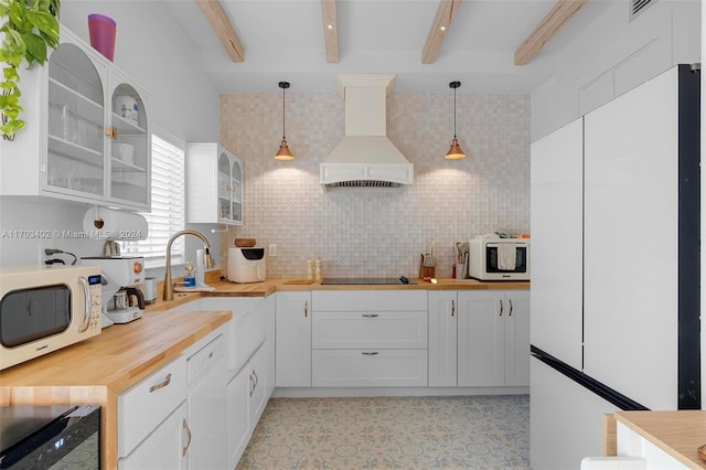 kitchen with white cabinets, decorative light fixtures, beam ceiling, and premium range hood