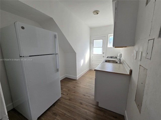 kitchen with dark hardwood / wood-style flooring, sink, and white fridge