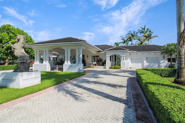 view of front of property featuring covered porch, a garage, and a front lawn