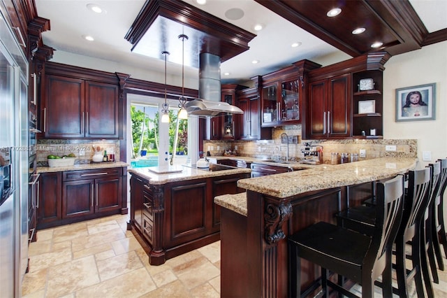 kitchen featuring decorative backsplash, island exhaust hood, kitchen peninsula, and hanging light fixtures