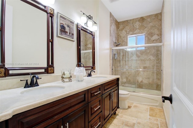 full bathroom featuring vanity, bath / shower combo with glass door, and toilet