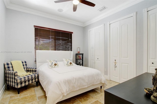 bedroom featuring ceiling fan, crown molding, and multiple closets