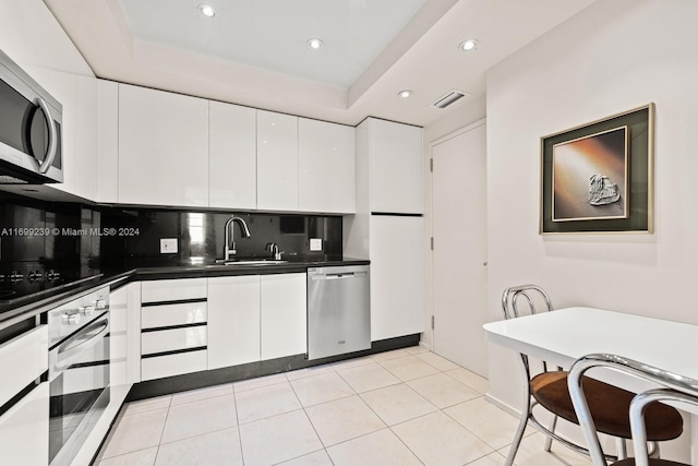 kitchen featuring sink, white cabinets, light tile patterned floors, and appliances with stainless steel finishes