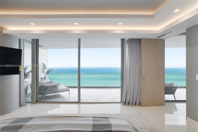 bedroom with multiple windows, a water view, light tile patterned flooring, and a view of the beach