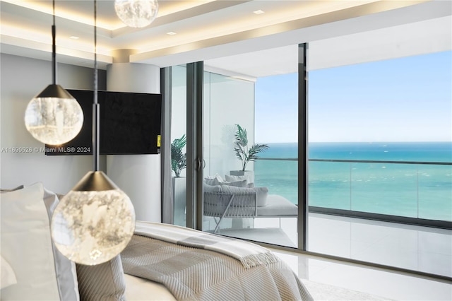 bedroom with expansive windows, a water view, and a tray ceiling