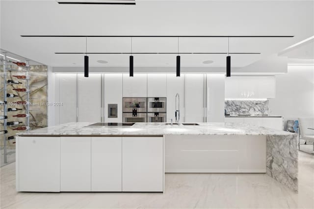 kitchen with white cabinets, black electric stovetop, sink, light stone countertops, and a kitchen island