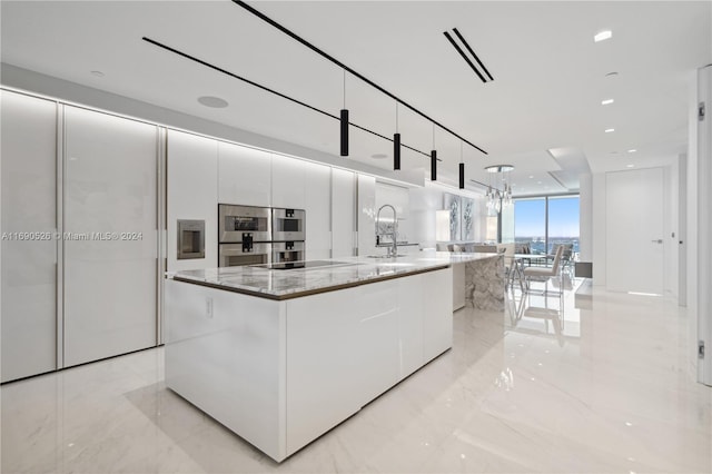 kitchen featuring appliances with stainless steel finishes, sink, stone counters, a center island, and white cabinetry