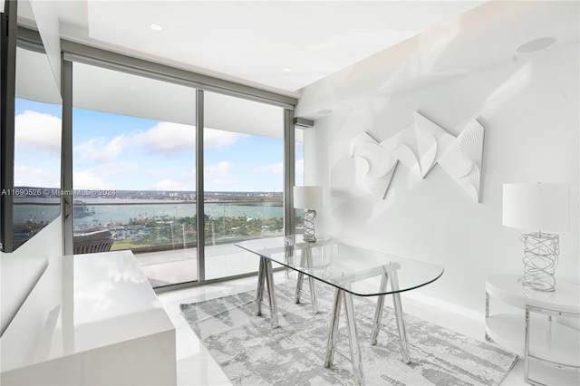 dining area with expansive windows, a water view, and a wealth of natural light