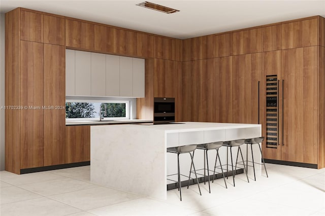 kitchen with a kitchen breakfast bar, light tile patterned flooring, a spacious island, and sink