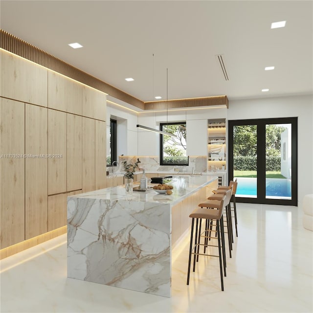 kitchen with a kitchen island, a kitchen bar, light stone countertops, and a wealth of natural light