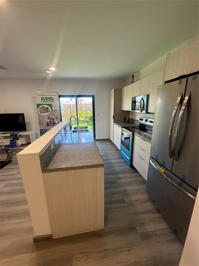 kitchen featuring sink, dark hardwood / wood-style flooring, an island with sink, and appliances with stainless steel finishes