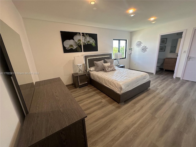 bedroom with hardwood / wood-style floors and ensuite bath