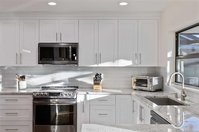 kitchen with backsplash, white cabinetry, sink, and stainless steel appliances