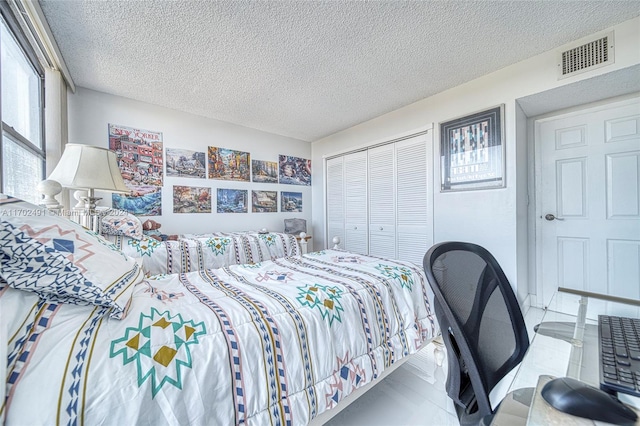 bedroom featuring light tile patterned flooring, a textured ceiling, and a closet