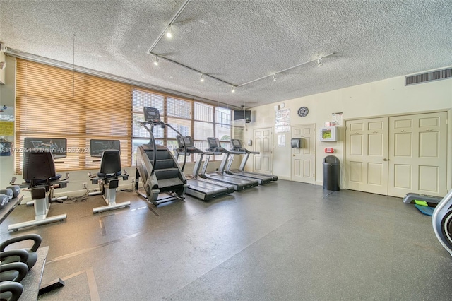 workout area with rail lighting and a textured ceiling