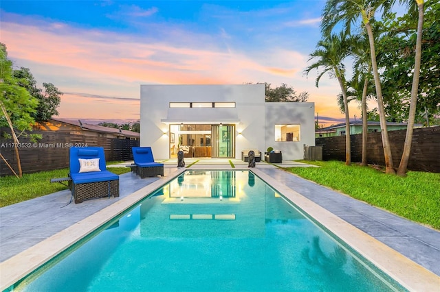 pool at dusk with central AC and a patio