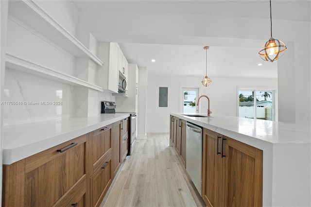 kitchen featuring sink, hanging light fixtures, stainless steel appliances, white cabinets, and light wood-type flooring