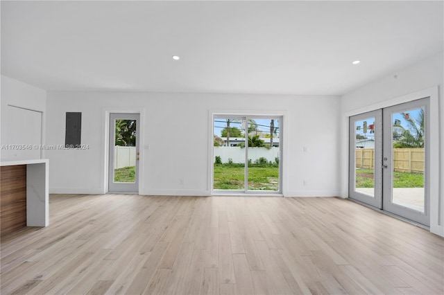 unfurnished room with light hardwood / wood-style floors, a wealth of natural light, and french doors