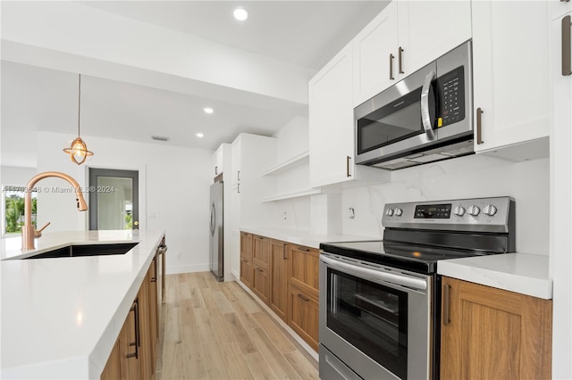 kitchen with white cabinets, stainless steel appliances, light hardwood / wood-style flooring, and sink