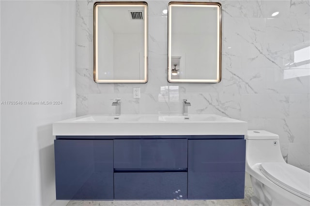 bathroom with vanity, tile walls, and toilet