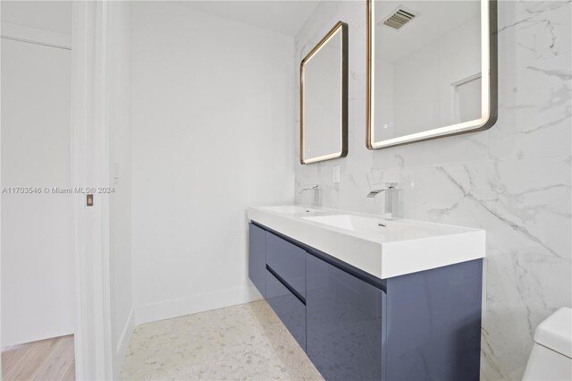 bathroom featuring vanity, hardwood / wood-style flooring, toilet, and tile walls