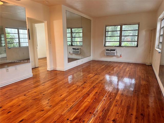 empty room featuring hardwood / wood-style flooring, a wealth of natural light, and a wall mounted AC