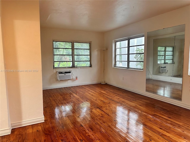 unfurnished room featuring hardwood / wood-style flooring, a wall unit AC, and a wealth of natural light