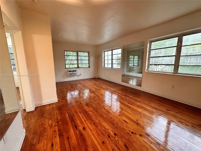 unfurnished living room with hardwood / wood-style flooring and a wall mounted air conditioner