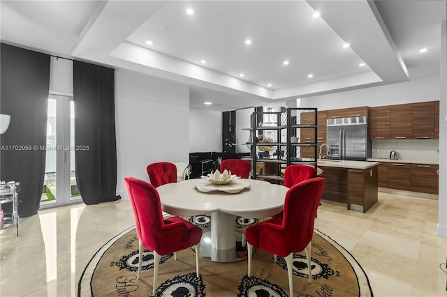 dining area with sink and a raised ceiling