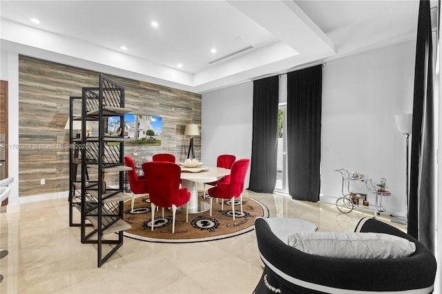 dining space featuring wooden walls and a raised ceiling