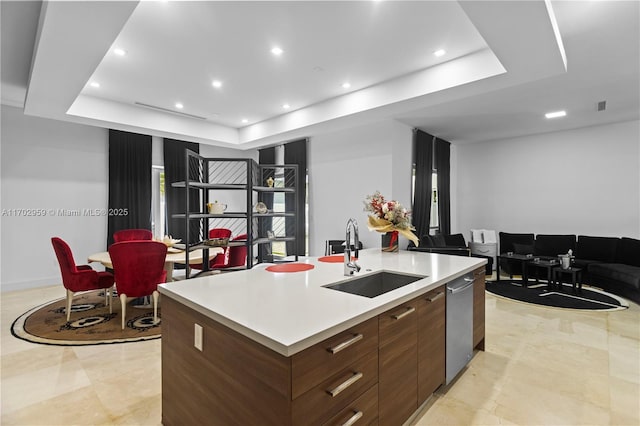 kitchen featuring a large island with sink, a raised ceiling, dishwasher, and sink