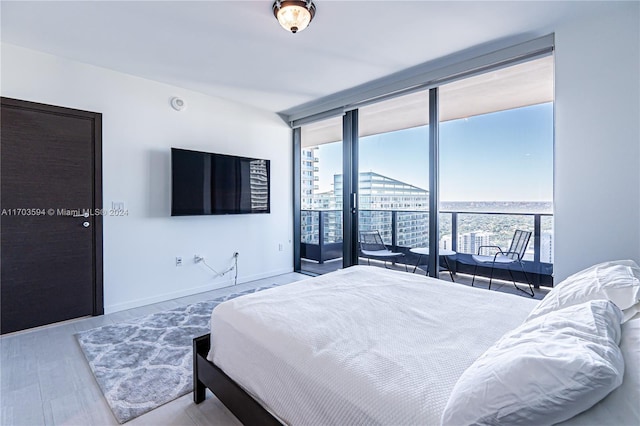 bedroom featuring access to outside, a wall of windows, light hardwood / wood-style floors, and multiple windows