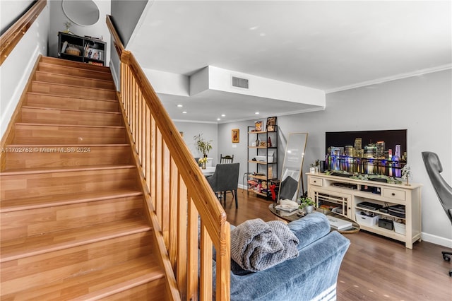 stairs featuring wood-type flooring and ornamental molding