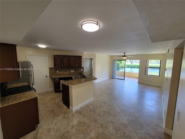 kitchen with a textured ceiling, tasteful backsplash, ceiling fan, and sink