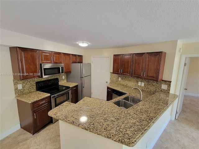 kitchen with kitchen peninsula, light stone counters, sink, and appliances with stainless steel finishes