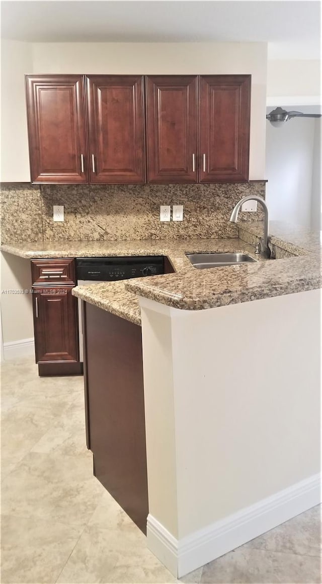 kitchen with kitchen peninsula, light stone countertops, sink, and tasteful backsplash