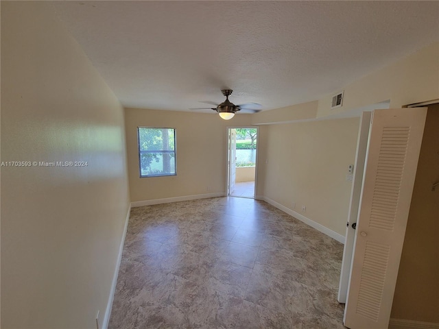 empty room with ceiling fan and a textured ceiling