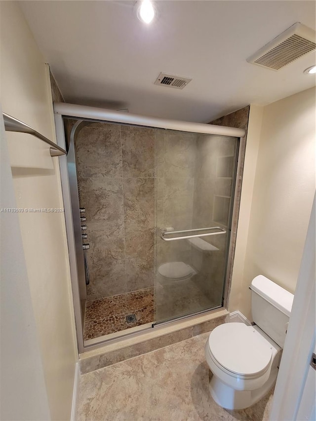 bathroom with toilet and a shower with door