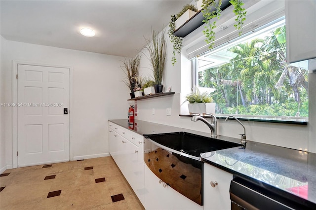 kitchen featuring white cabinets, light tile patterned flooring, stainless steel dishwasher, and sink