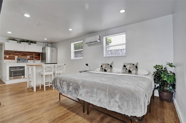 bedroom featuring light hardwood / wood-style floors, stainless steel refrigerator, and a wall mounted AC